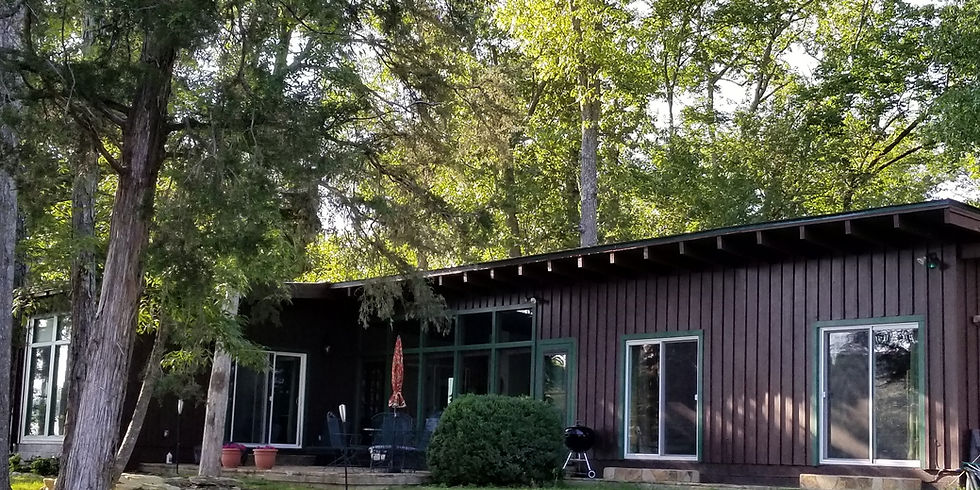 Lakeside exterior of Guntersville Getaway single-level home with lake-facing patio and large windows facing the water