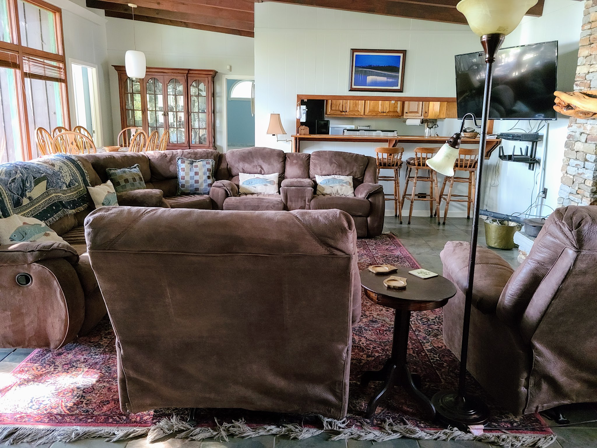 Open living area with sectional sofa, fish throw pillows, and oak kitchen bar at Guntersville Getaway lake house